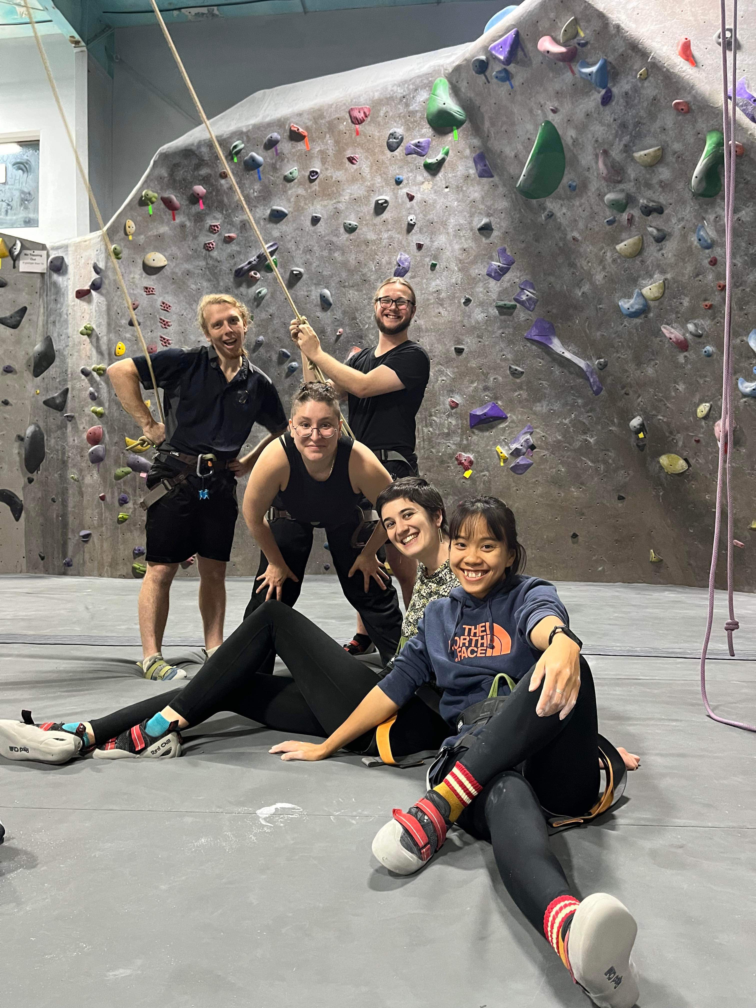 Summiteers pose at indoor rock climbing.