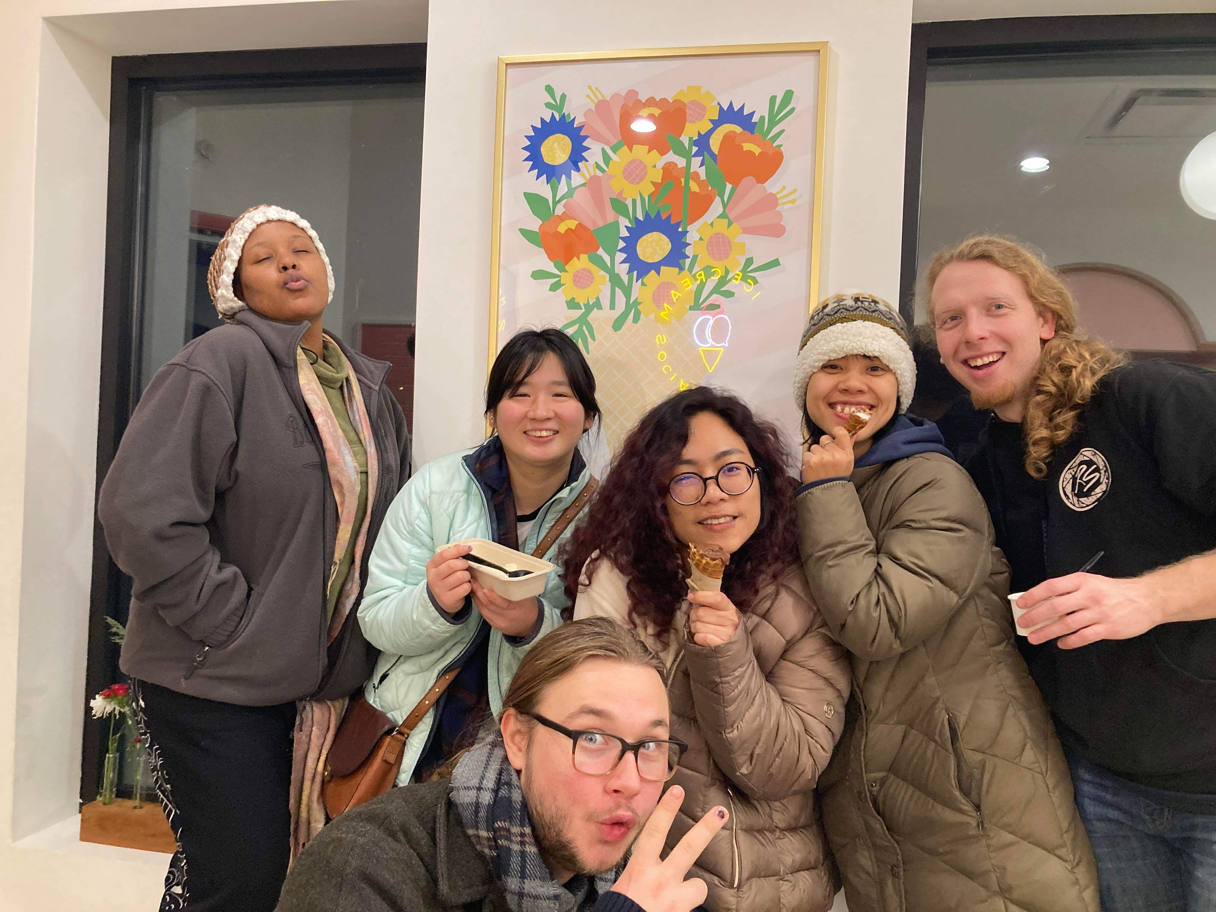 Six Summiteers stand in front of a floral painting